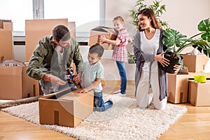 Young couple moving in a new home with their children helping them