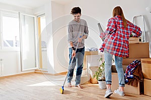 Young couple moving in new home. Unpacking box containers and cleaning. photo