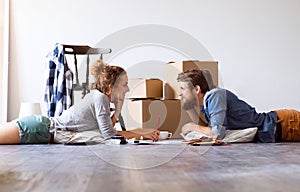 Young couple moving in new house, lying on the floor.