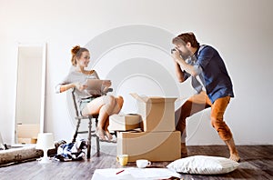 Young couple moving in new house, taking photos.