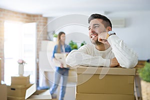 Young couple moving to a new home, handsome man smiling leaning on cardboard boxes