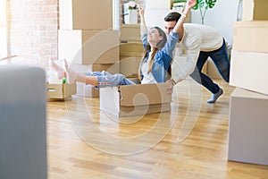 Young couple moving to a new home, having fun riding cardboard boxes