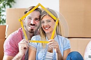 Young couple moving to new home, holding house together and smiling