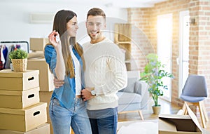 Young couple moving to a new home, hugging in love showing keys of new apartment smiling very happy