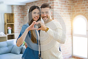 Young couple moving to a new home, hugging in love showing keys of new apartment smiling very happy