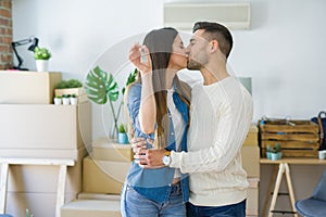 Young couple moving to a new home, hugging in love showing keys of new apartment smiling very happy