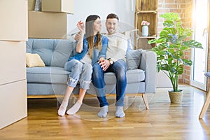 Young couple moving to a new home, hugging in love showing keys of new apartment smiling very happy