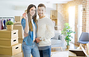 Young couple moving to a new home, hugging in love showing keys of new apartment smiling very happy