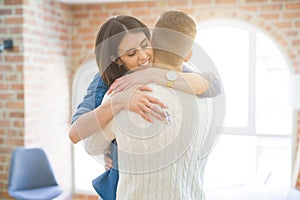 Young couple moving to a new home, hugging in love showing keys of new apartment smiling very happy