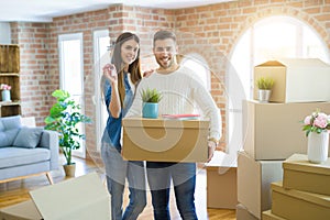 Young couple moving to a new home, hugging in love showing keys of new apartment smiling very happy