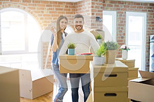 Young couple moving to a new home, hugging in love showing keys of new apartment smiling very happy