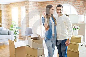 Young couple moving to a new home, hugging in love showing keys of new apartment smiling very happy