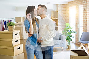 Young couple moving to a new home, hugging in love showing keys of new apartment smiling very happy