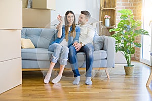 Young couple moving to a new home, hugging in love showing keys of new apartment smiling very happy