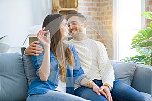 Young couple moving to a new home, hugging in love showing keys of new apartment smiling very happy