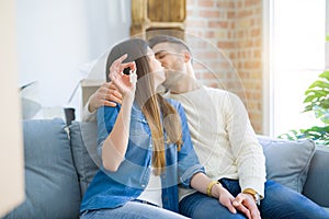 Young couple moving to a new home, hugging in love showing keys of new apartment smiling very happy