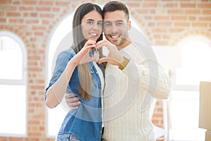 Young couple moving to a new home, hugging in love showing keys of new apartment smiling very happy