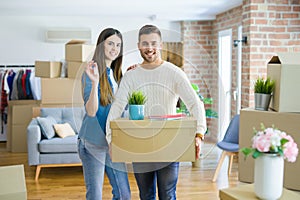 Young couple moving to a new home, hugging in love showing keys of new apartment smiling very happy