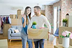 Young couple moving to a new home, hugging in love showing keys of new apartment smiling very happy