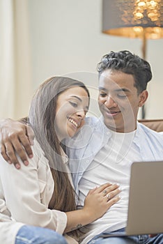 Young couple moving to a new home relaxing sitting on the sofa using computer laptop, smiling happy for moving to new apartment