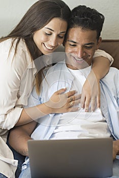 Young couple moving to a new home relaxing sitting on the sofa using computer laptop, smiling happy for moving to new apartment