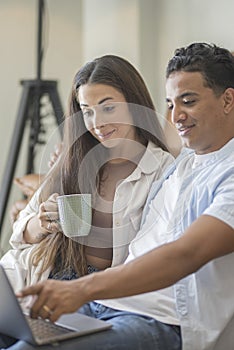 Young couple moving to a new home relaxing sitting on the sofa using computer laptop, smiling happy for moving to new apartment