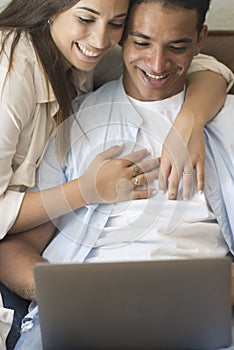 Young couple moving to a new home relaxing sitting on the sofa using computer laptop, smiling happy for moving to new apartment