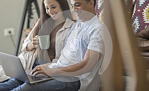 Young couple moving to a new home relaxing sitting on the sofa using computer laptop, smiling happy for moving to new apartment