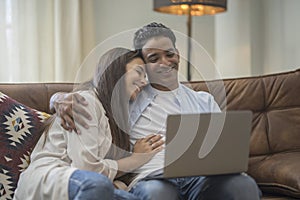 Young couple moving to a new home relaxing sitting on the sofa using computer laptop, smiling happy for moving to new apartment