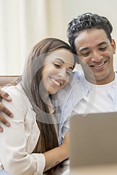 Young couple moving to a new home relaxing sitting on the sofa using computer laptop, smiling happy for moving to new apartment