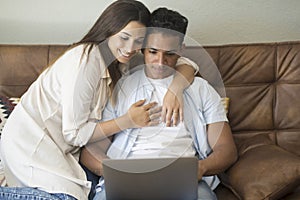 Young couple moving to a new home relaxing sitting on the sofa using computer laptop, smiling happy for moving to new apartment