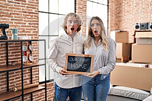 Young couple moving to a new home in shock face, looking skeptical and sarcastic, surprised with open mouth