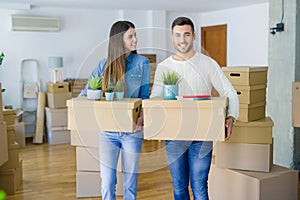 Young couple moving to a new home, smiling happy holding cardboard boxes at new apartment