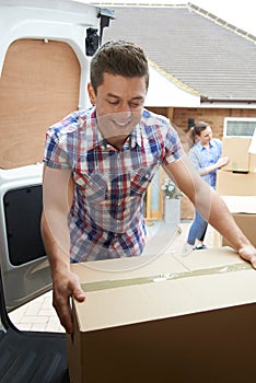 Young Couple Moving In To New Home Unloading Removal Van