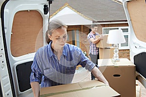 Young Couple Moving In To New Home Unloading Removal Van