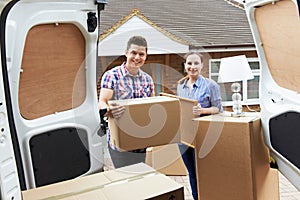 Young Couple Moving In To New Home Unloading Removal Van