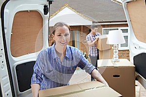 Young Couple Moving In To New Home Unloading Removal Van