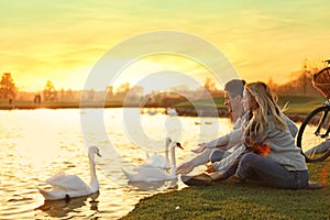 Young couple near lake with swans. Perfect place for picnic