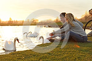 Young couple near lake with swans. Perfect place for picnic