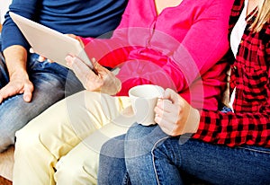 Young couple with old woman sitting on couch and watching something on tablet