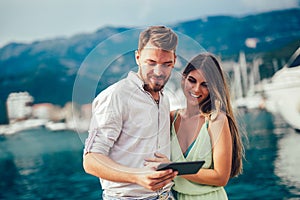 Young couple outdoor against sea boats with tablet