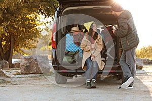 Young couple packing camping equipment into car trunk