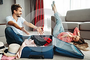 Young couple packing their suitcases for vacation