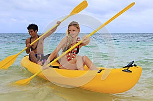 A young couple paddle a kayak in Hawaii