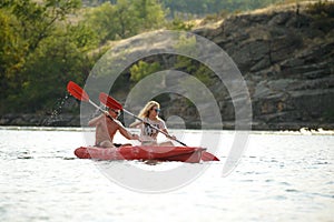 Young Couple Paddling Kayak on Beautiful River or Lake in the Evening