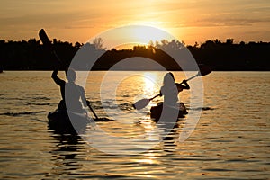 Young Couple Paddling Kayaks on the Beautiful River or Lake under Dramatic Evening Sky at Sunset