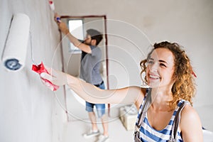 Young couple painting walls in their new house.