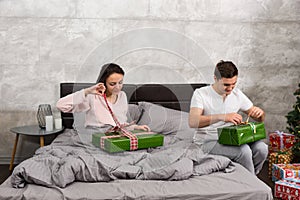 Young couple in pajamas unpacking their presents while sitting o