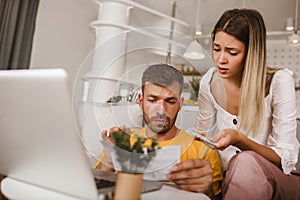 Young couple paying bills online using laptop and credit card