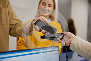 Young couple paying for doctor appointment at clinic reception using smartphone